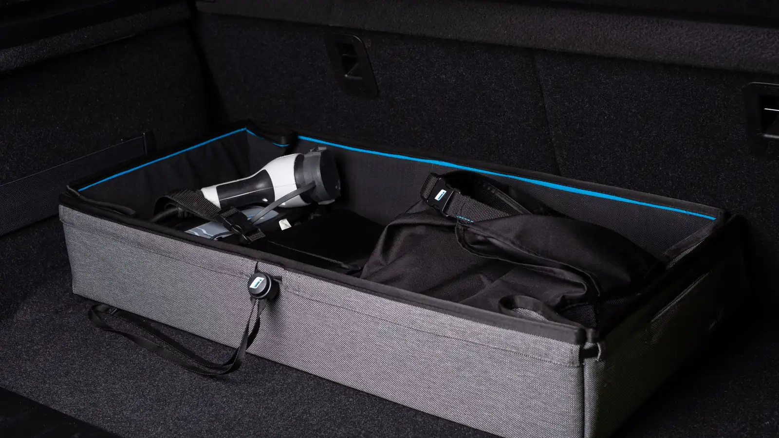Aufgeräumter Kofferraum mit Organizer, Ladekabel und Tasche – Auto vor dem Parken am Flughafen vorbereiten